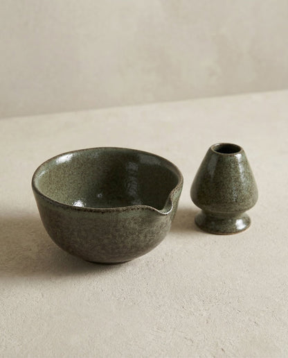Yeşil matcha kasesi ve çırpıcı standı, sade zeminde